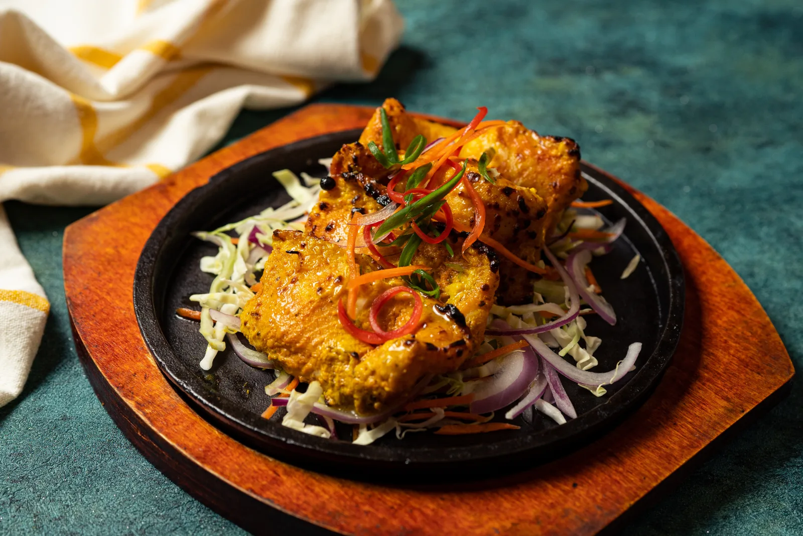 Fish tikka on a sizzling platter with onions